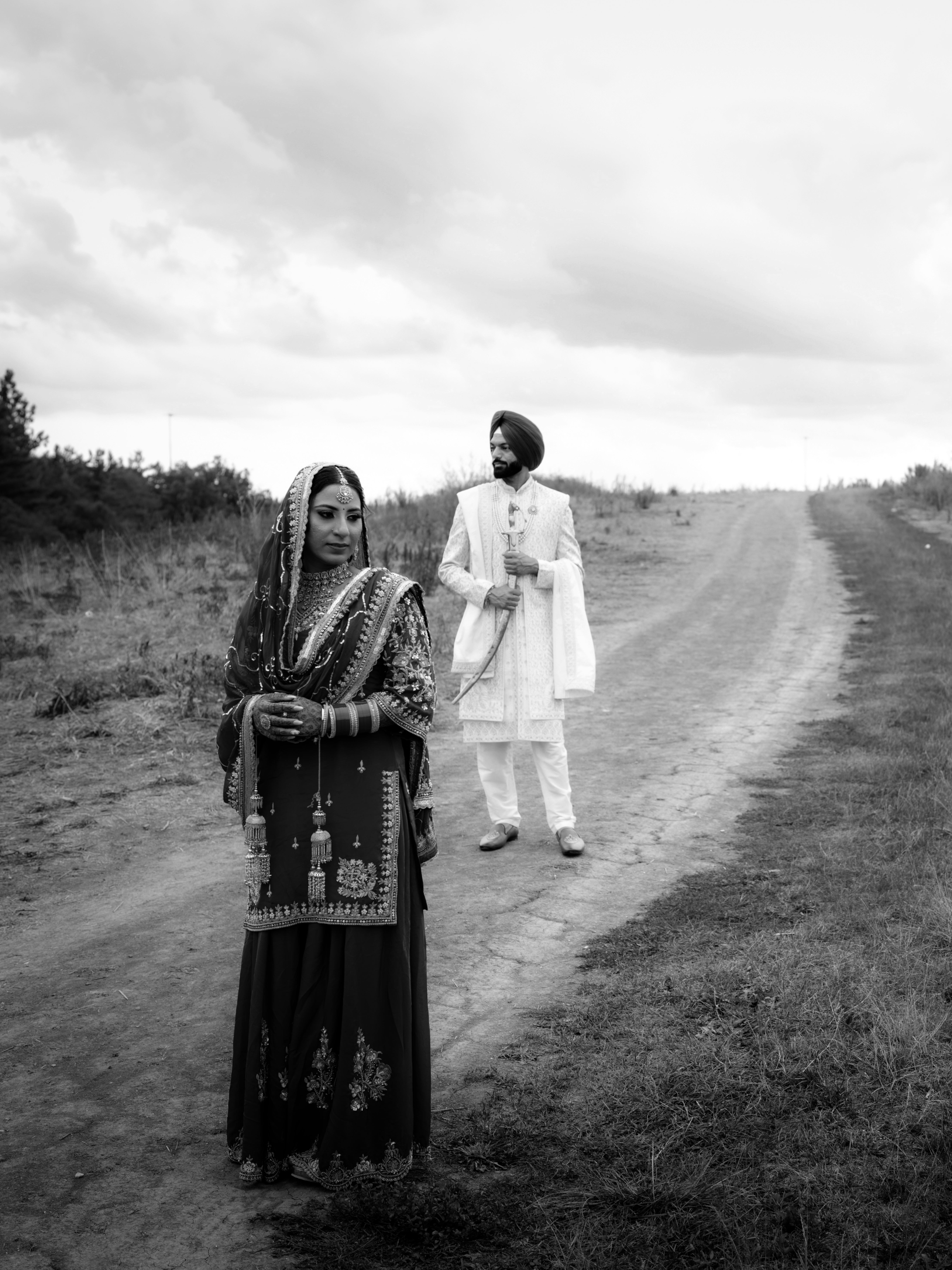 Bride and groom on a quiet country road, photographed in black and white